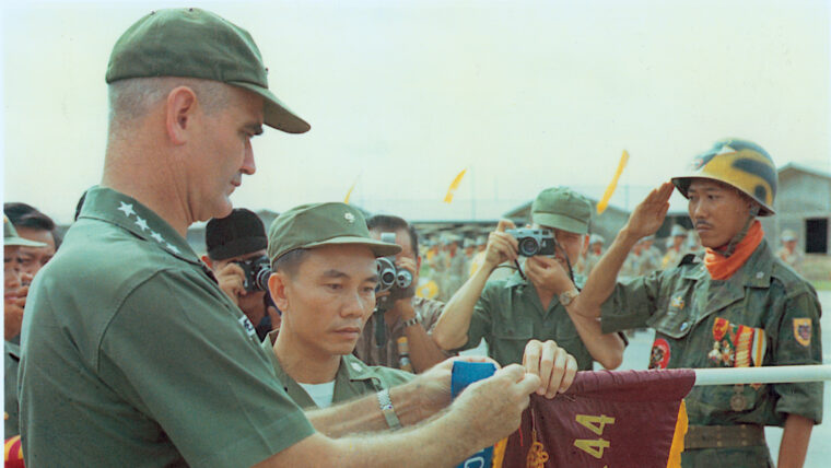 Westmoreland decorates the standard of a fighting unit in Vietnam. He left the country in 1968.