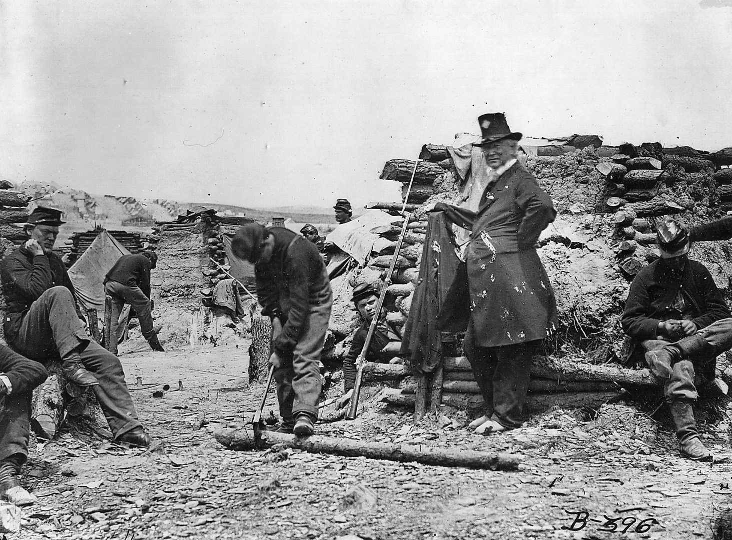 Soldiers chop wood and use mud to build winter quarters. The older soldier, second from the right, is probably an officer, judging from his dress and age.