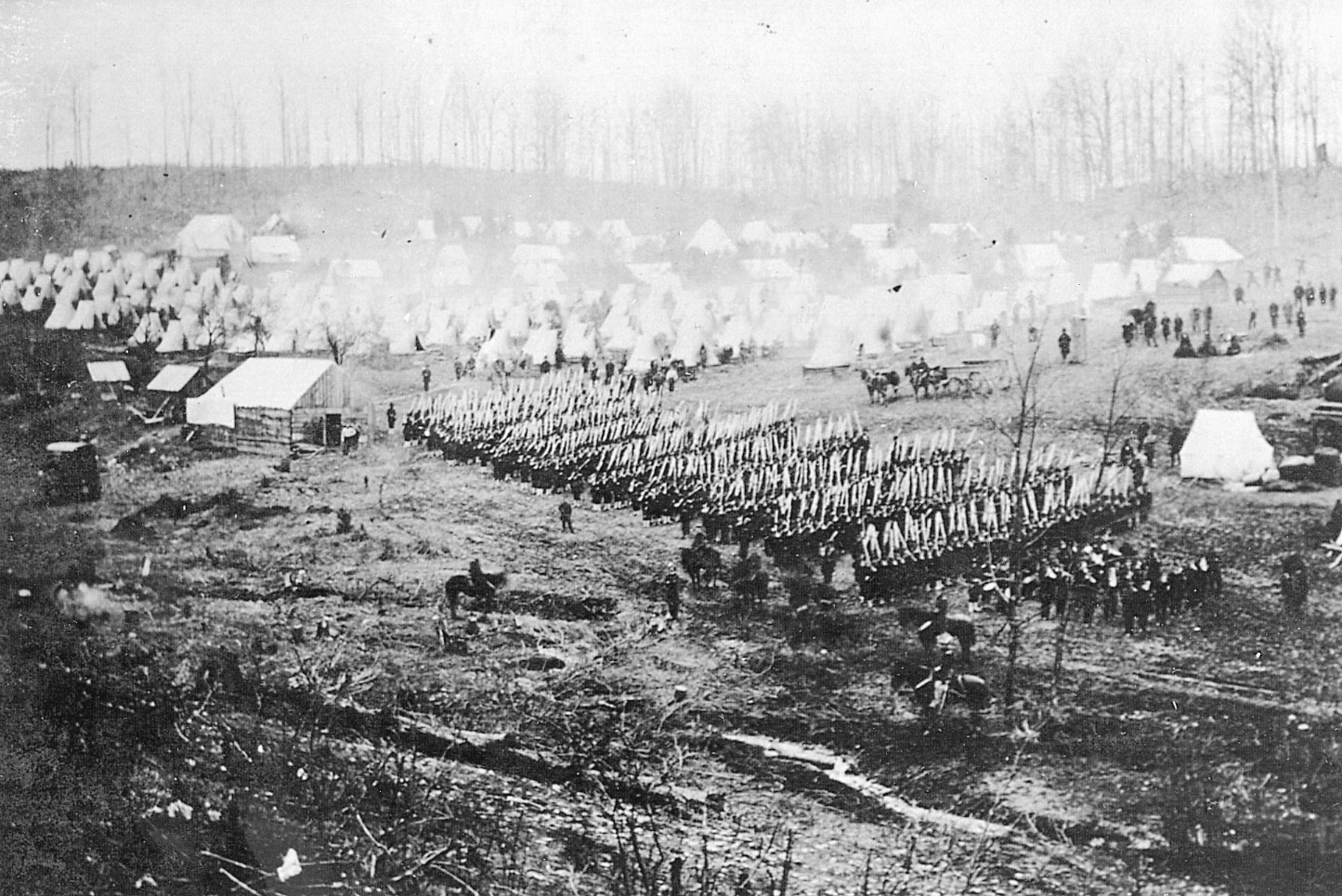 With rifles bristling at left shoulder arms, a Union regiment marches in camp. Due to the presence of tents rather than huts, one could judge that this picture was probably taken early in the war.