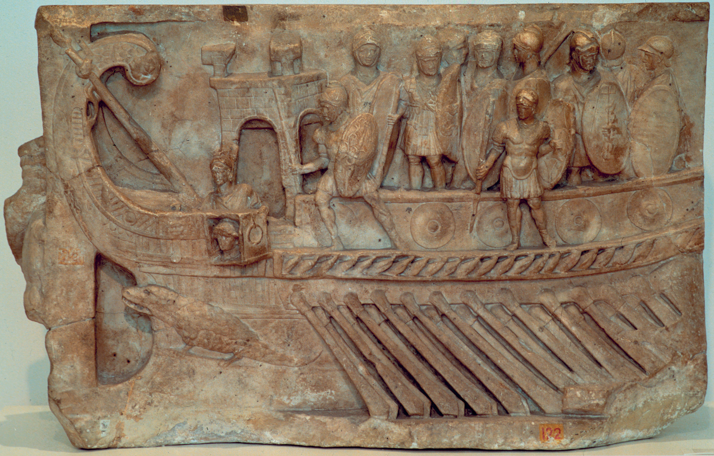 A Roman galley makes its way by oar power. One of its functions was to deliver Roman land-trained legionaries to the fight where they would board and seize enemy ships. 