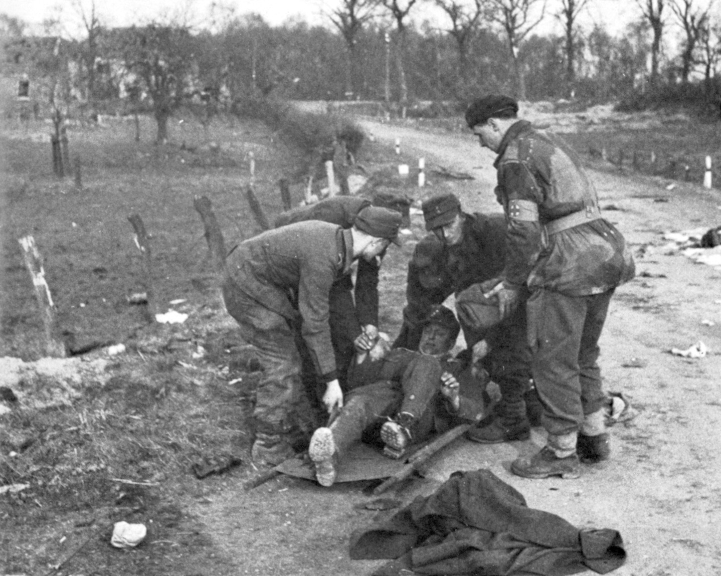 German prisoners place a wounded comrade on a stretcher under the watchful eye of a medical orderly.