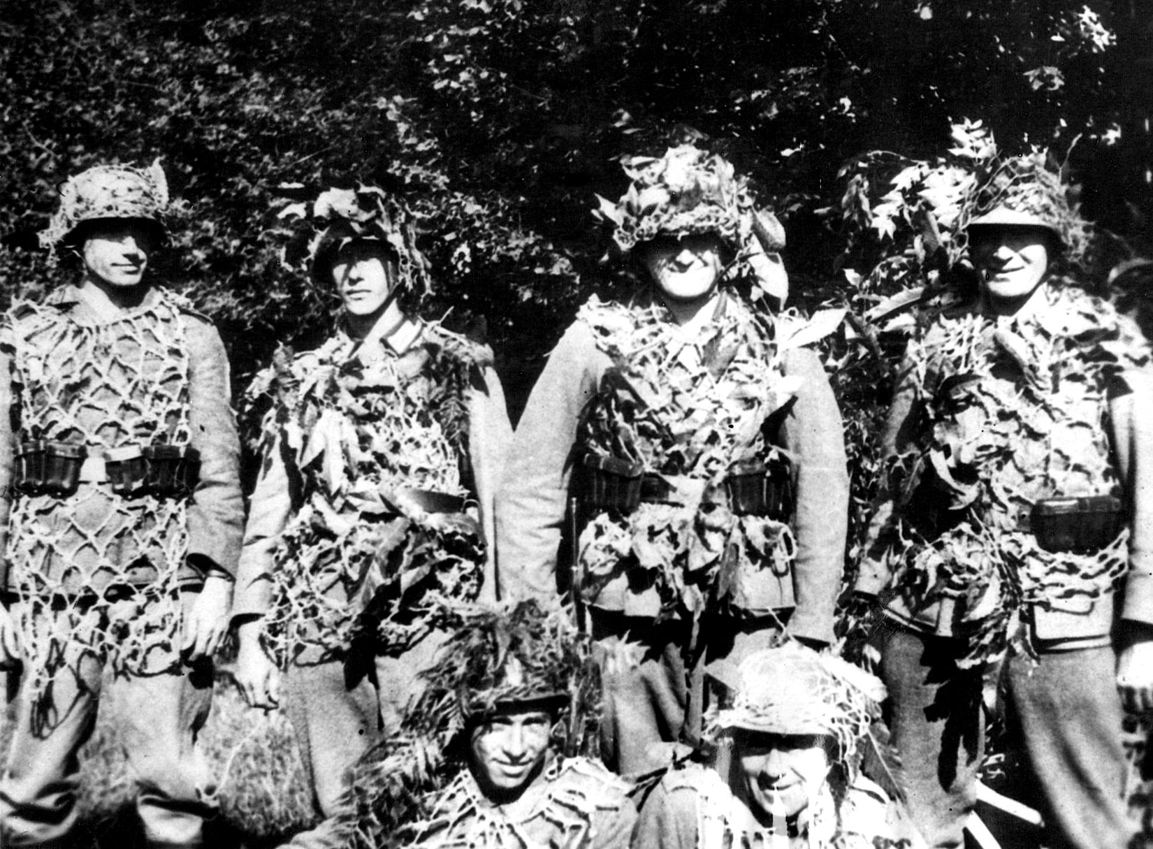 In a photo discarded by retreating German soldiers, Wehrmacht personnel pose wearing camouflaged helmets and smocks over their uniforms.