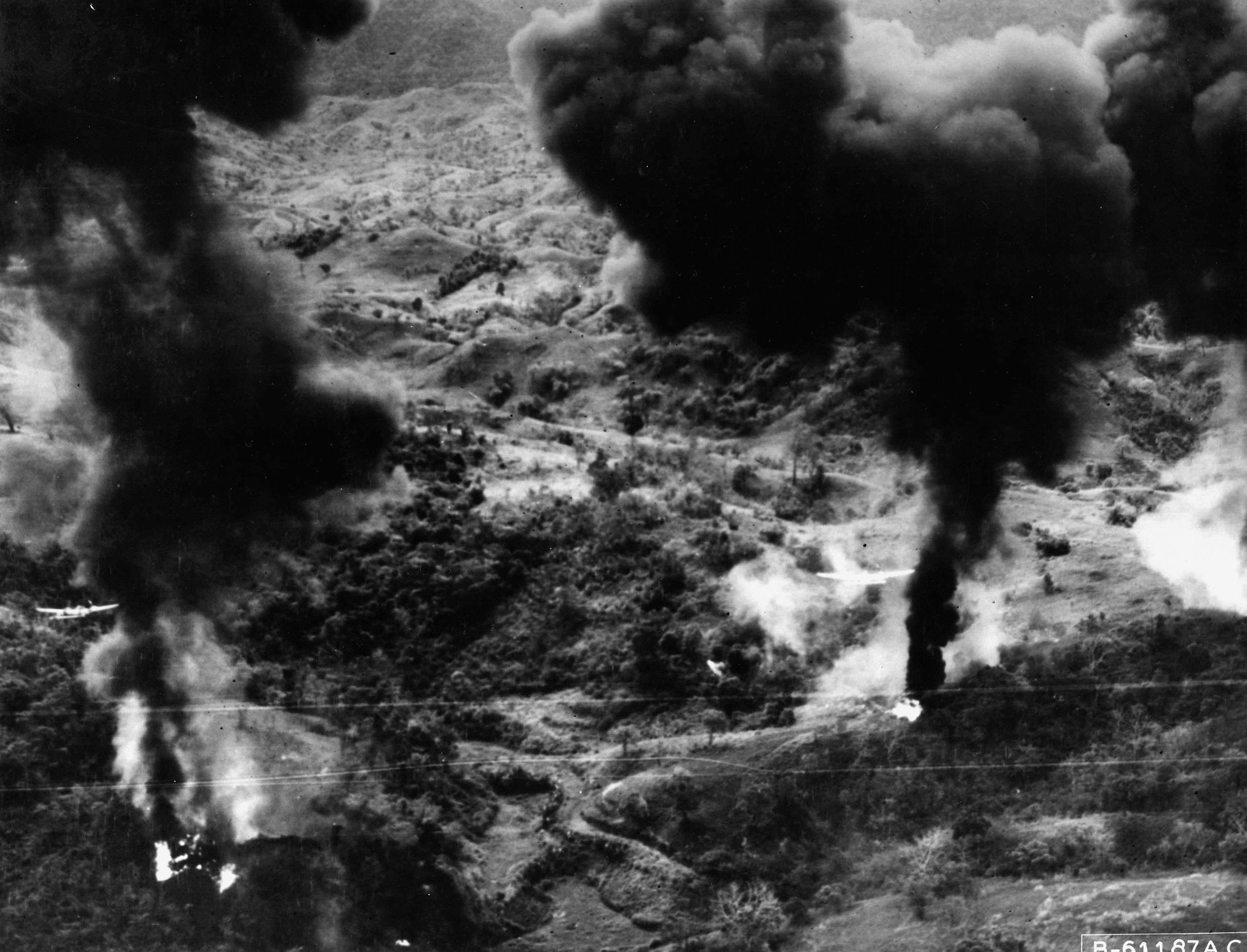 Smoke and flames engulf Japanese defenses in the rugged terrain near Ipo Dam following an attack by fighter bombers of the U.S. Fifth Air Force. The effectiveness of the attack allowed ground troops to advance two miles virtually without resistance.