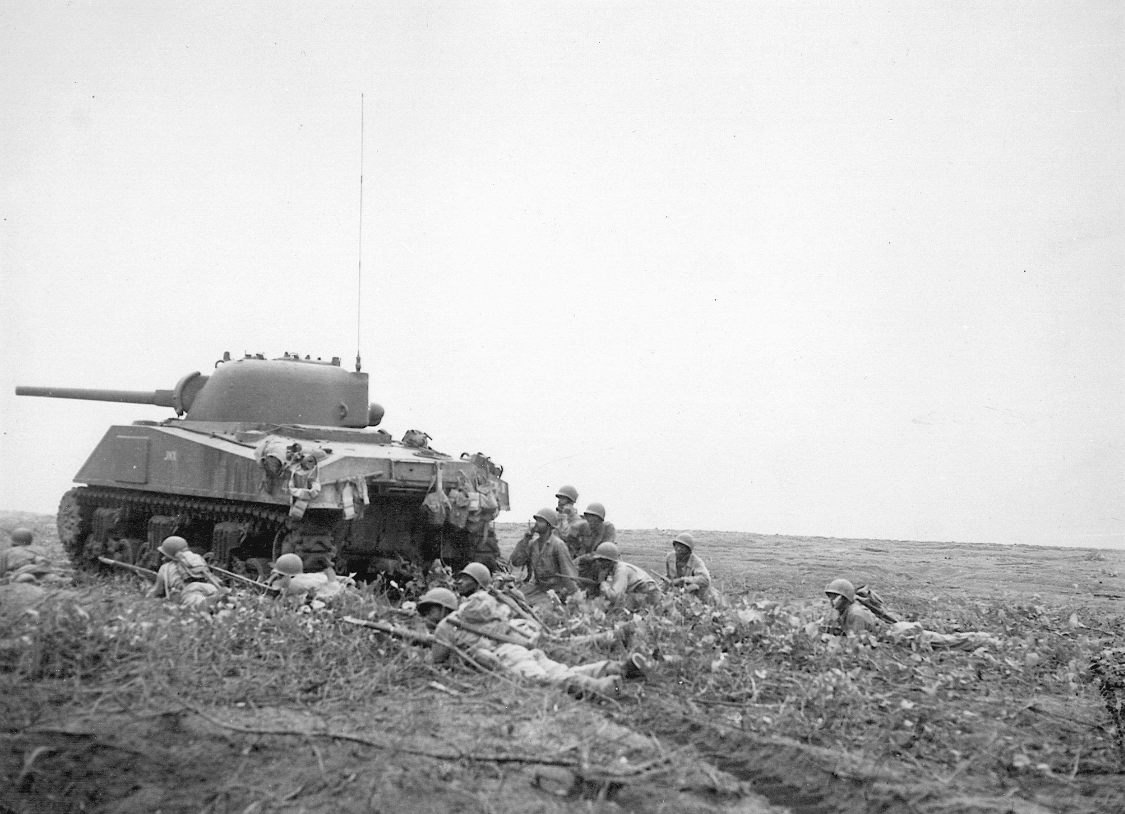 African American troops of the 24th Infantry Regiment advance behind a U.S. Sherman tank at Empress Bay, Bougainville. 