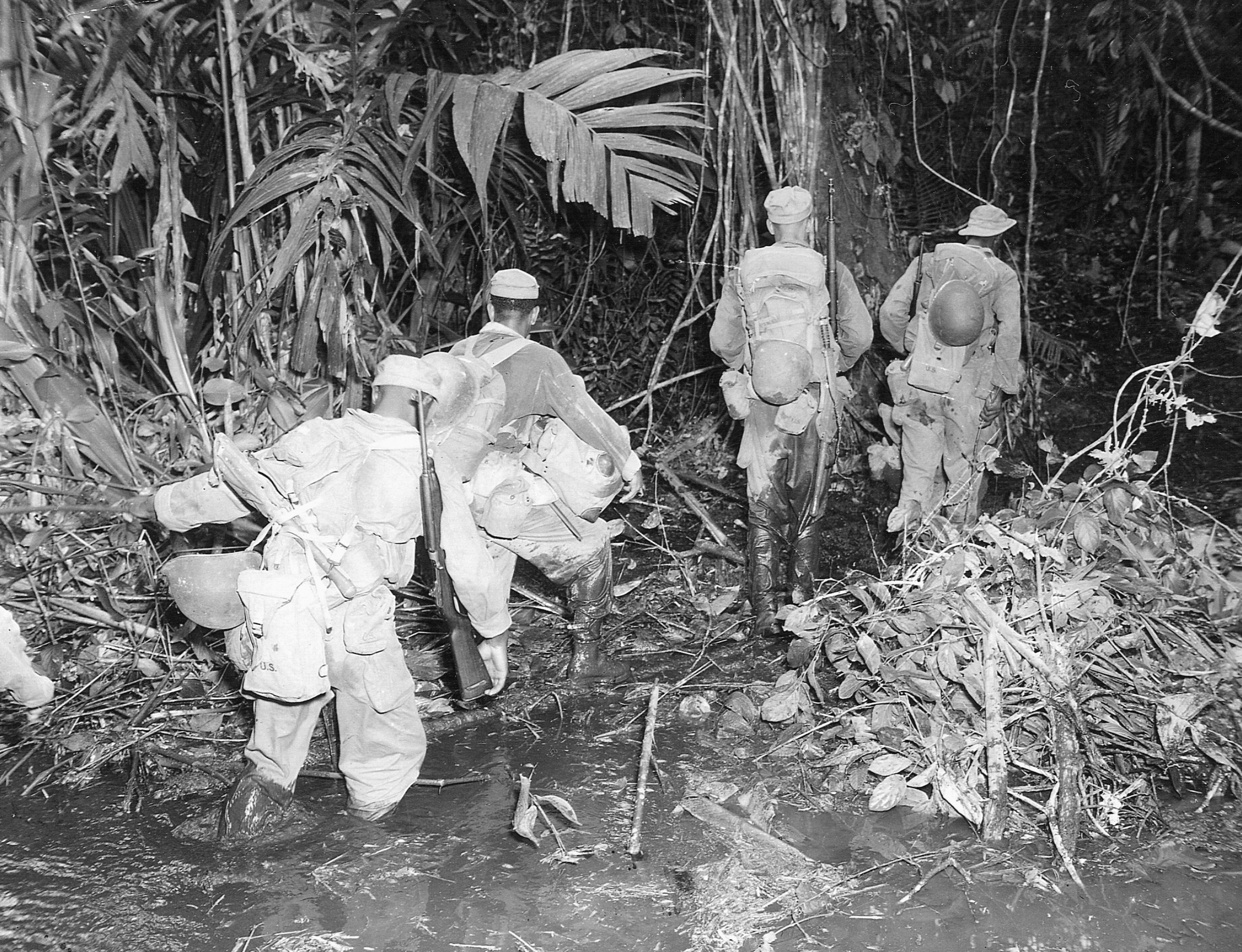 Laden with combat necessities, soldiers of the 93rd Infantry Division push through the dense jungle of the East West Trail at Bougainville.