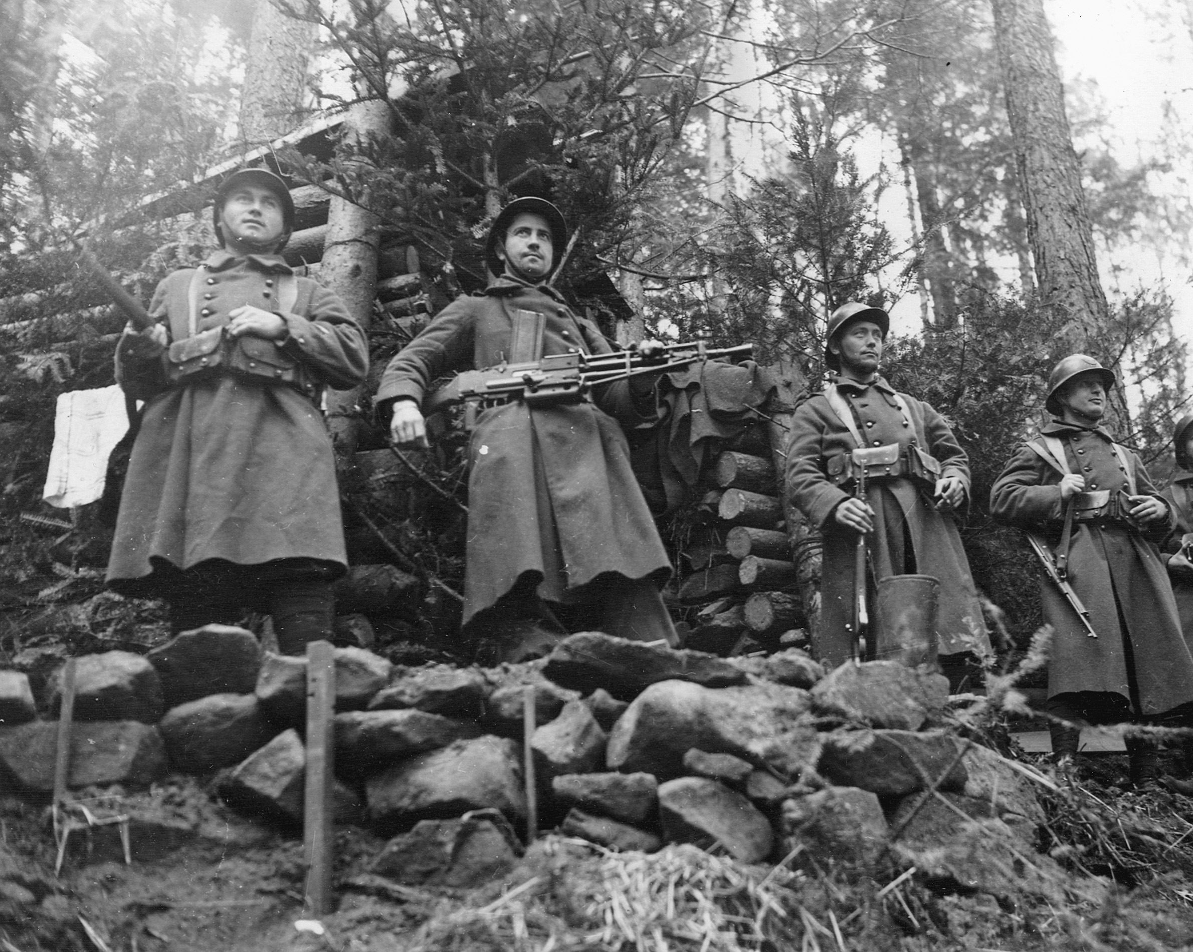 Rifles in hand, a French patrol proudly poses for the camera in front of a log blockhouse fortification atop a rocky outcrop in Belgium.