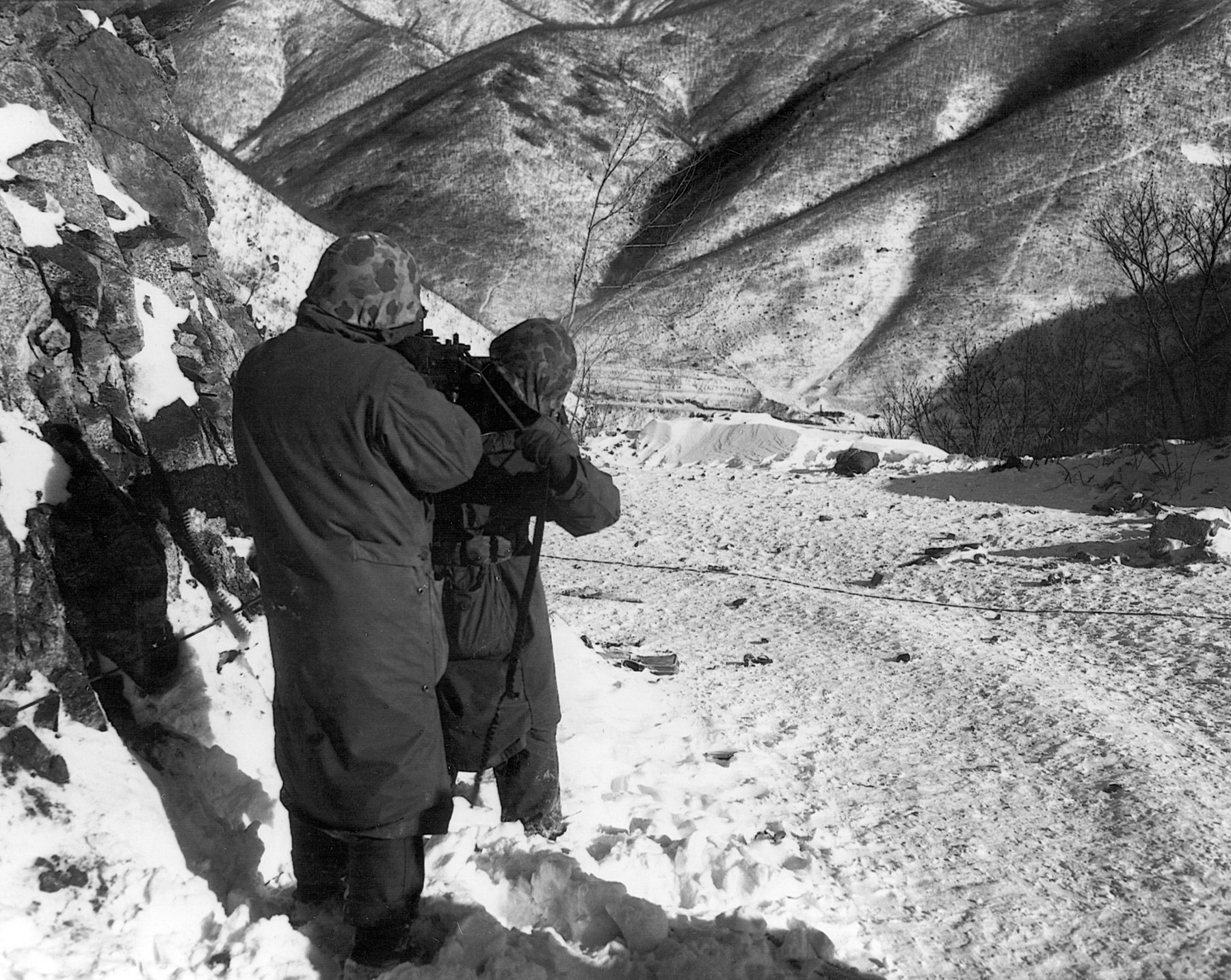 Two Marines line up a light machine gun on a Communist position in late December 1950. The weather was bitter cold.