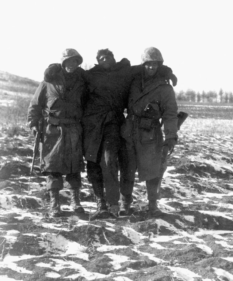 Late on November 27, two Marines help a wounded buddy back to an aid station.