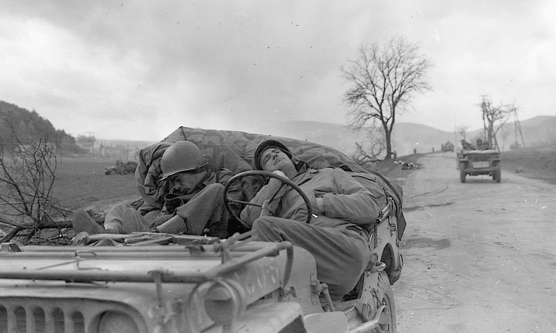 Soldiers with the 6th Armored Division catch a few winks on the outskirts of the burning town of Waldkappel, Germany.