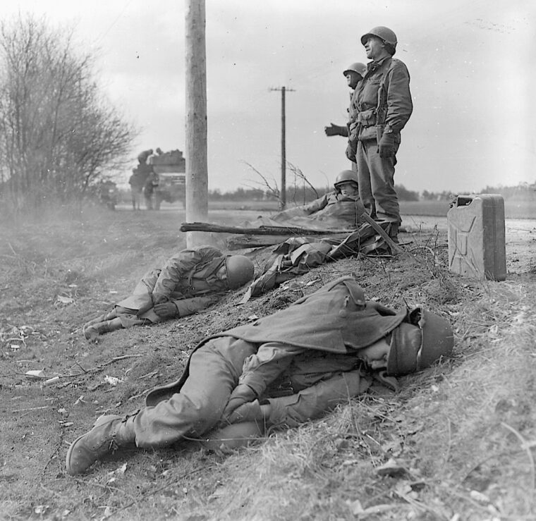 Armored infantrymen of the 8th Armored Division rest along a roadside in Boisheim, Germany.