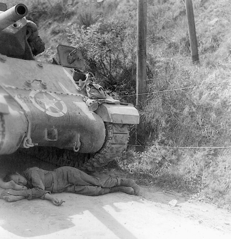 A tanker naps under his Sherman while waiting for engineers to finish a bridge in Calpenzzano, Italy.