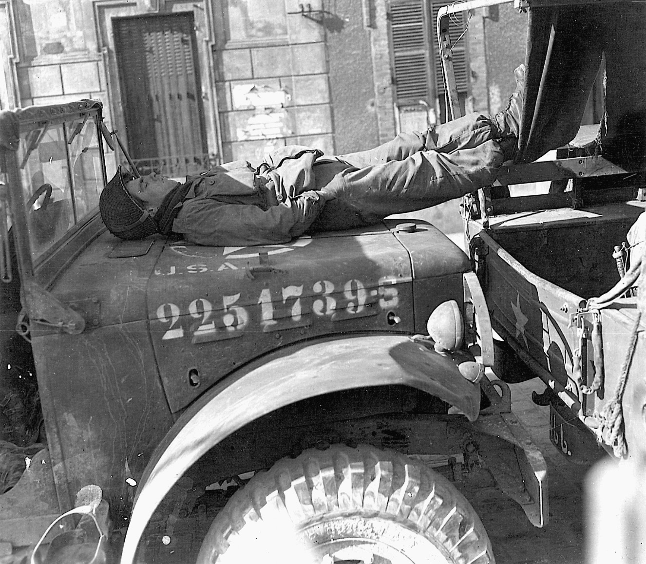 A paratrooper of the 17th Airborne uses the hood of a weapons carrier for an impromptu bed.