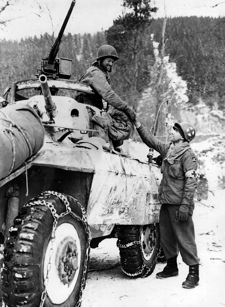 A soldier from the 11th Armored Division shares a handshake with a member of the 84th Infantry in Houffalize.