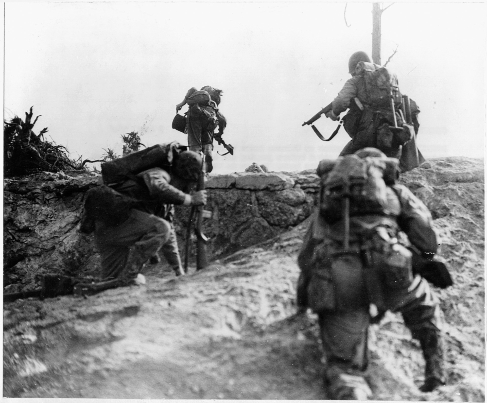 Marines advance on the run. Two carry communications wire and radio equipment to stay in contact with other units.