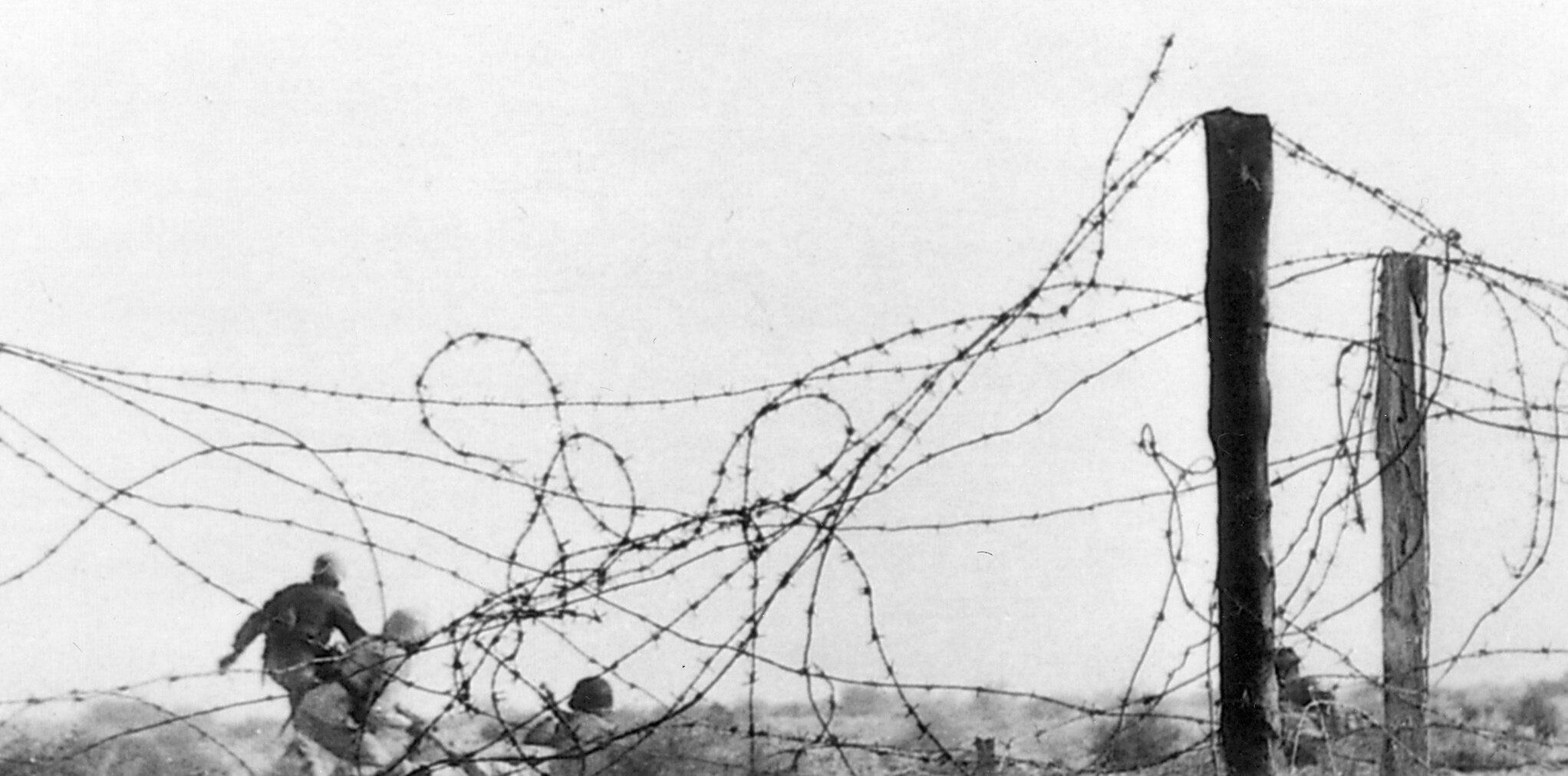 Advancing on Tobruk, German soldiers move through a tangle of barbed wire.