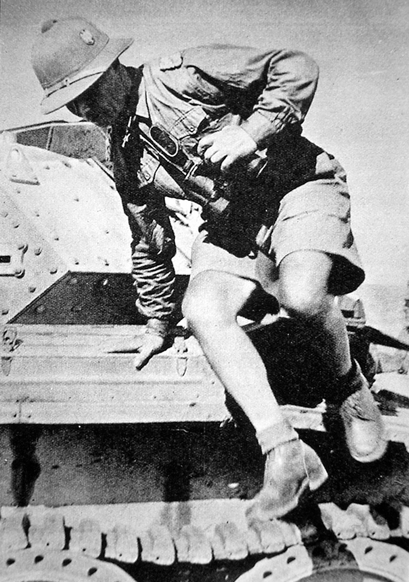 Rommel, dressed in tropical helmet and shorts, inspects a captured British Crusader tank. 
