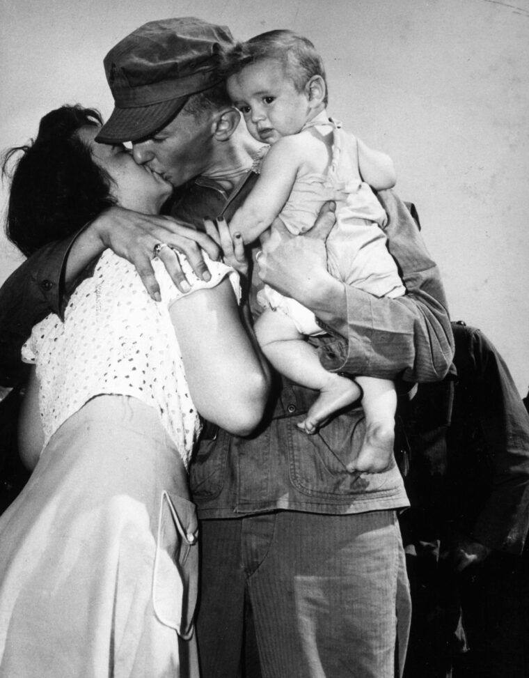 Corporal John W. Simms bids goodbye to his wife and child as he prepares to leave for Korea in 1950.