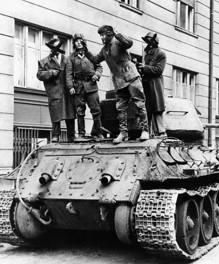 Soviet tankers are forced at gunpoint to disable their vehicle. The freedom fighters disabled the tanks by throwing stones and steel bars into their wheel treads.