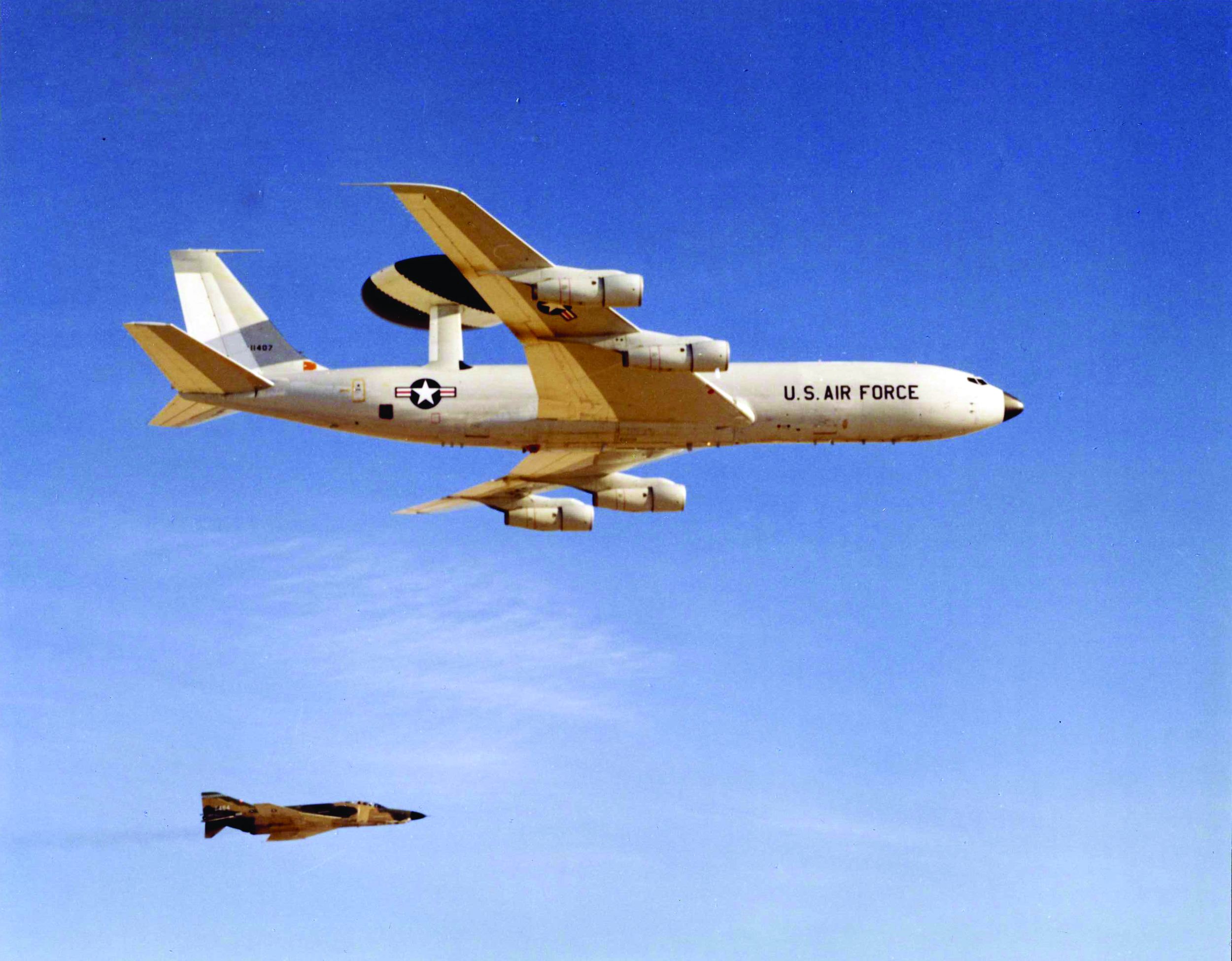 An E-3A AWACS aircraft flies near Edwards Air Force Base, California, shadowed by a RF-4E chase plane.