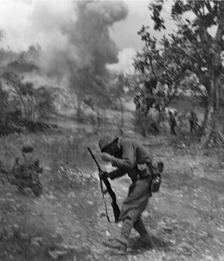 A Marine recoils in shock after taking pieces of shrapnel from a Japanese mortar.