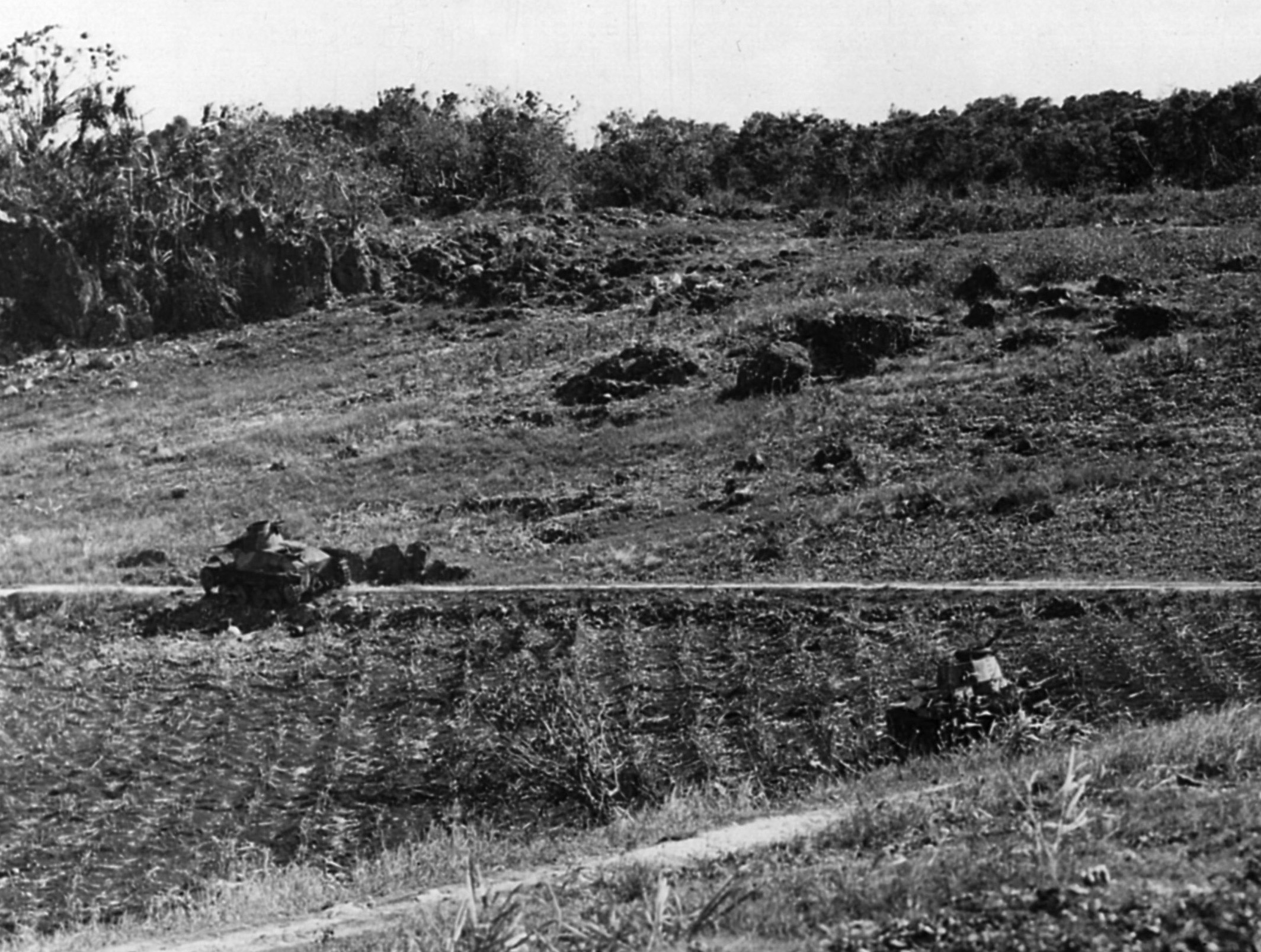 Scorched earth and burned-out shells of Japanese tanks are all that remain at this hillside on Saipan.
