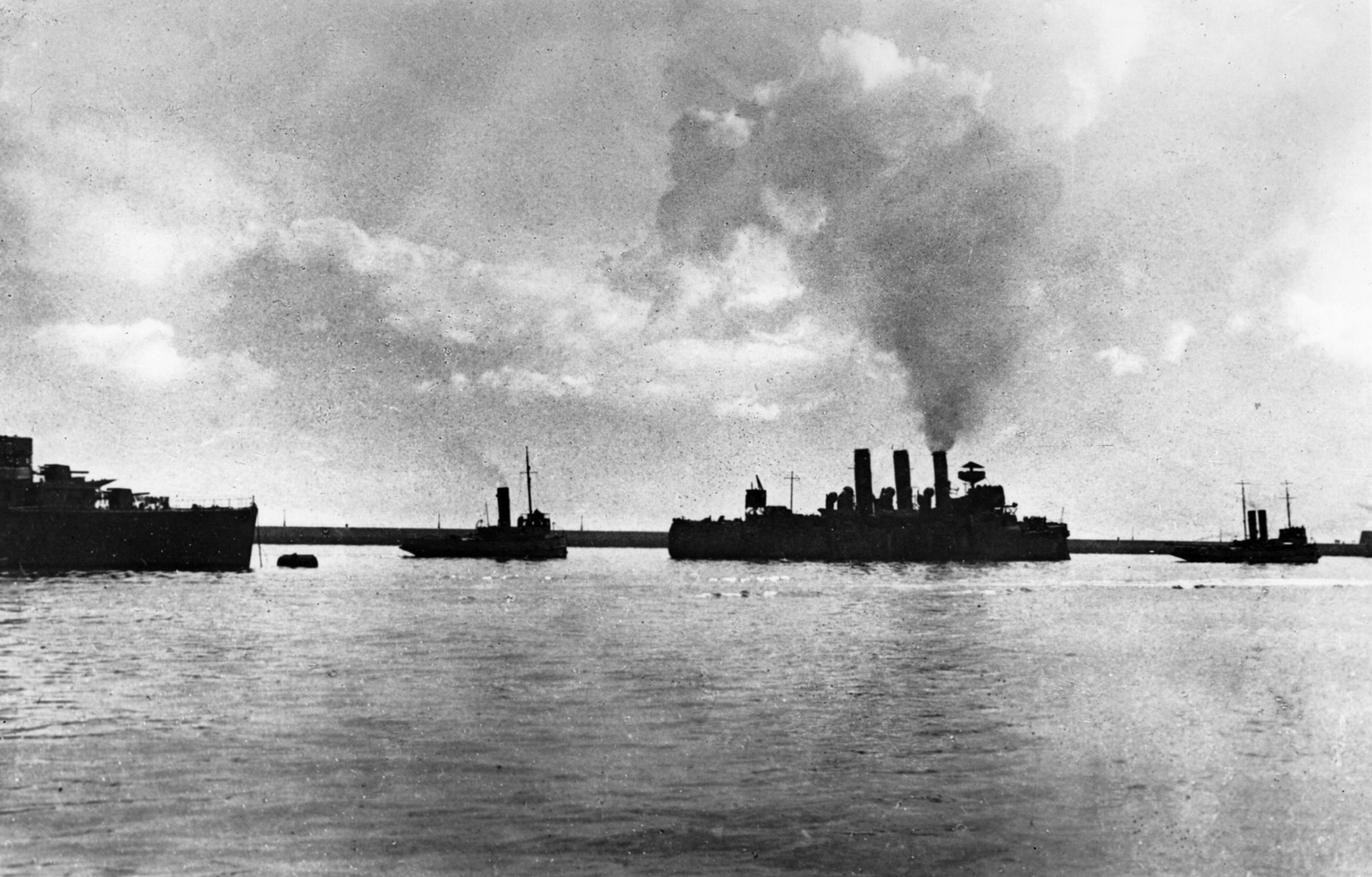 Wounded but unbowed, HMS Vindictive is towed out of Dover Harbor for her final blocking effort at Ostend.