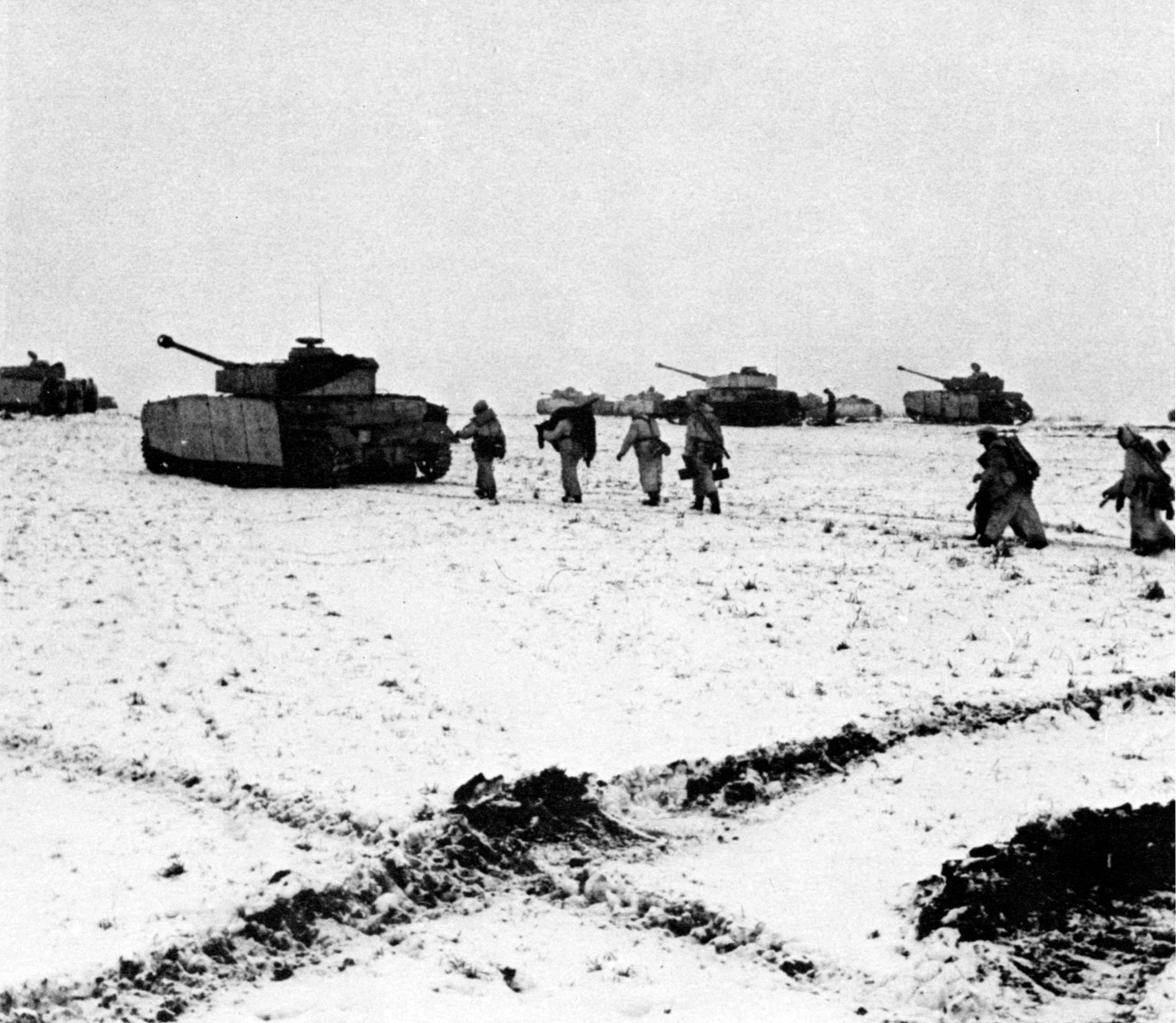 Advancing across a snow-covered Russian steppe, German soldiers clad in white camouflage snowsuits support tanks and self-propelled assault vehicles.