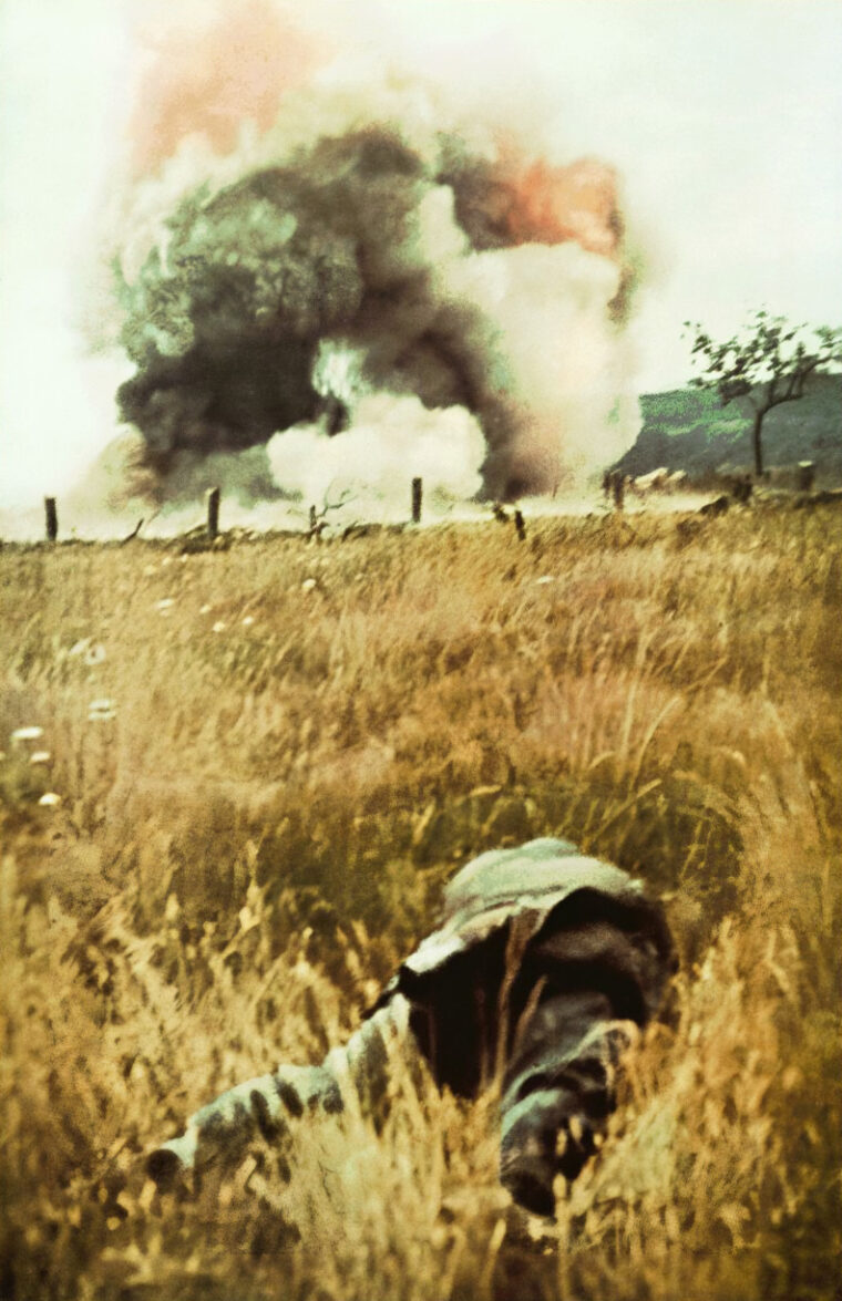 A German soldier on the move against a fortress of the Maginot Line crouches as French artillery shells explode.