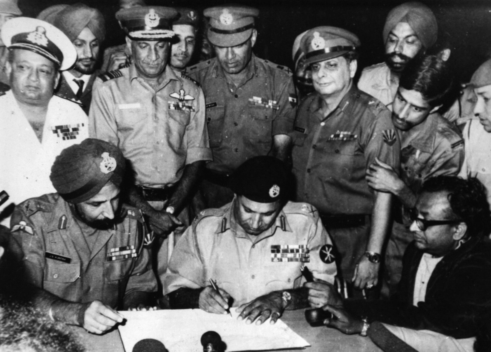 Defeated Pakistani General A.A.K. Niazi, center, signs the surrender document on December 16, 1971. Indian General J.F.R. Jacob peers over Niazi’s left shoulder.