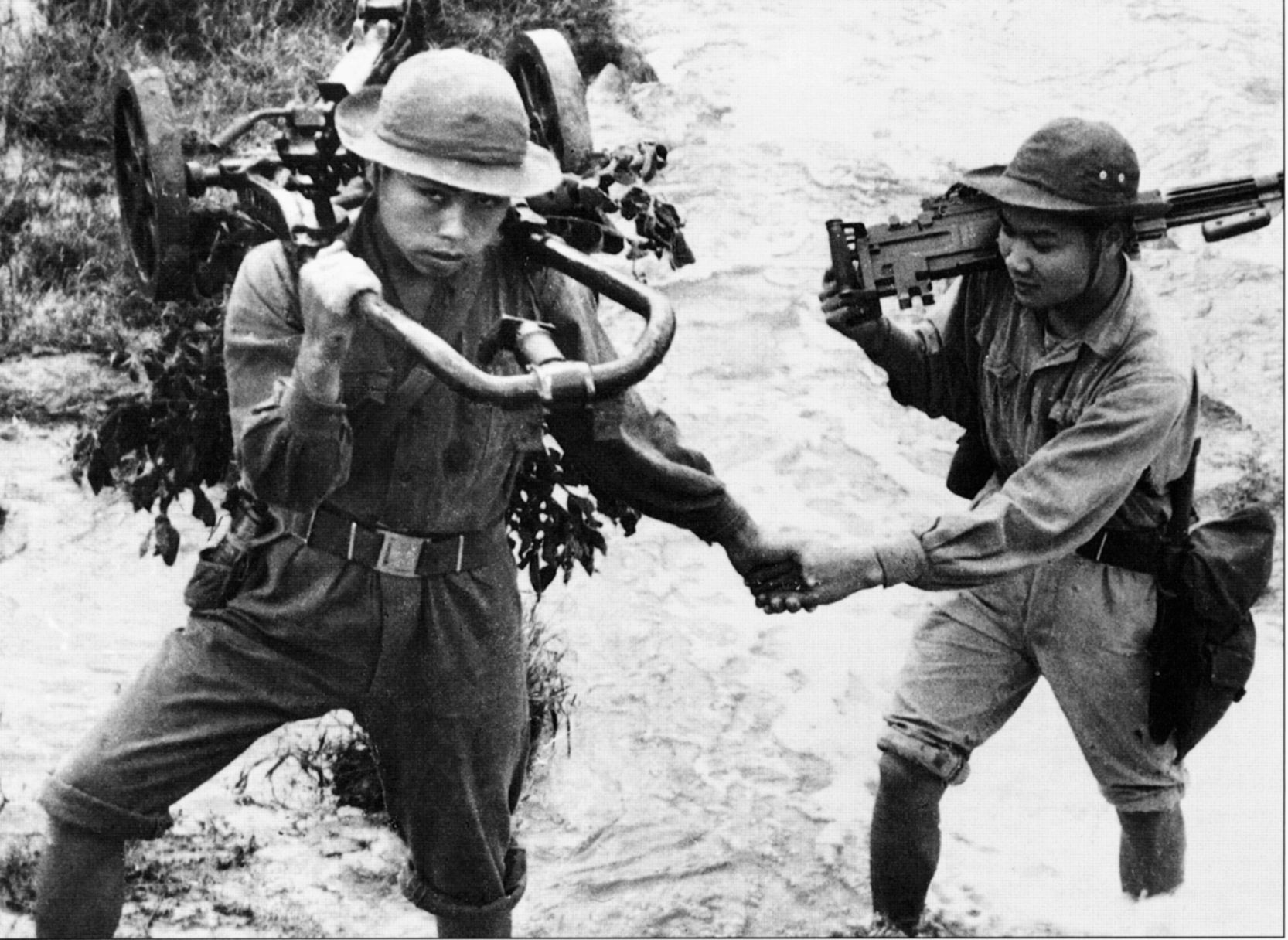 Two North Vietnamese regulars cross a river carrying their weapons on their back during the assault on Hue.
