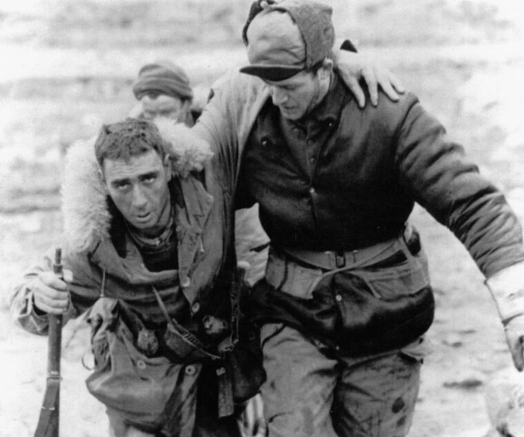 A wounded Canadian rifleman is helped to a frontline aid station by one of his fellow infantrymen.