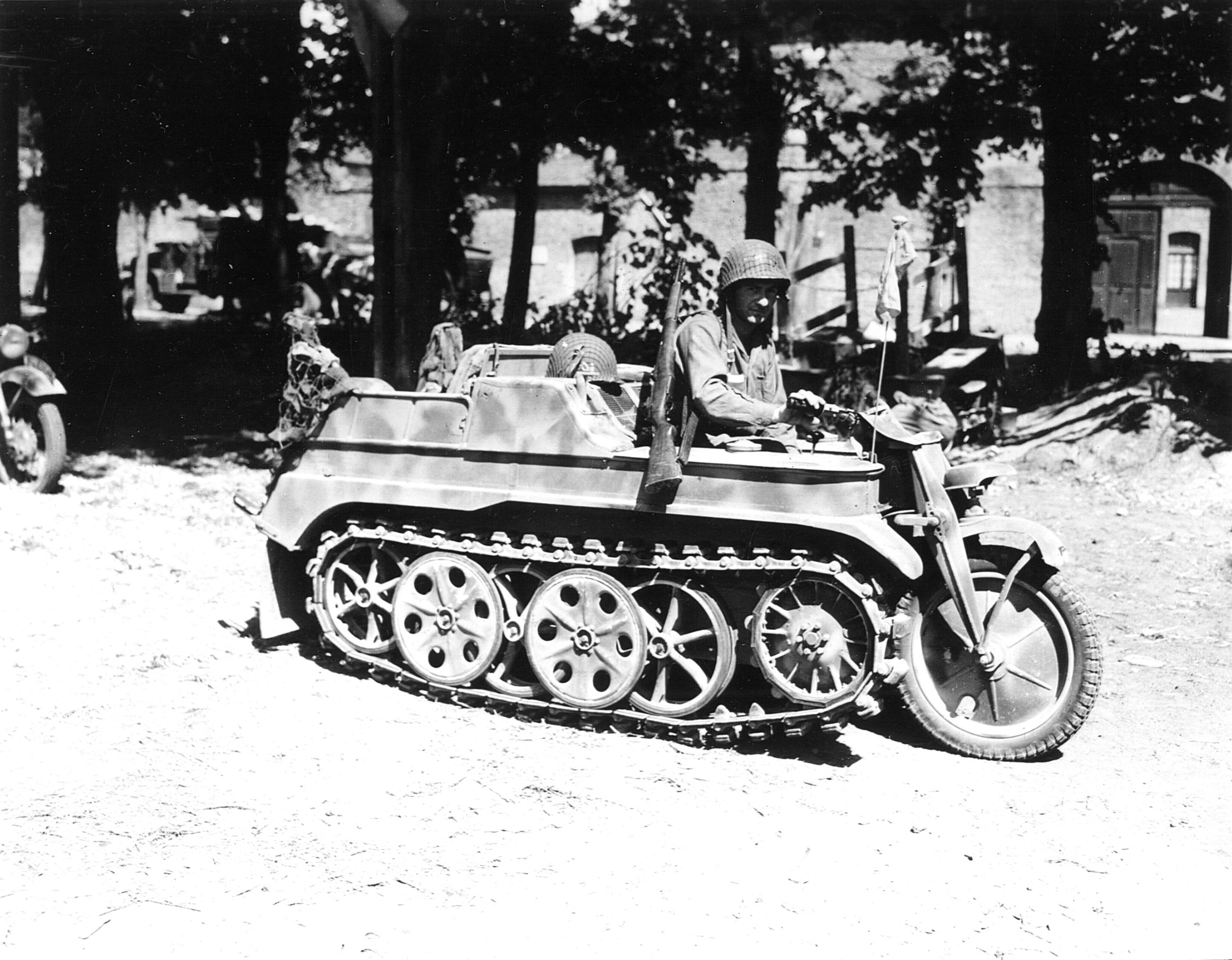 A paratrooper with the 101st Airborne Division tries out a German half-track motorcycle, known as a kettenkrad, in Carentan, France.