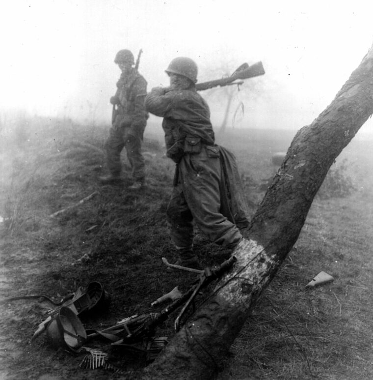 To insure these captured German weapons won’t be used again, a soldier of the 10th Armored Division breaks them against a tree, March 7, 1945.