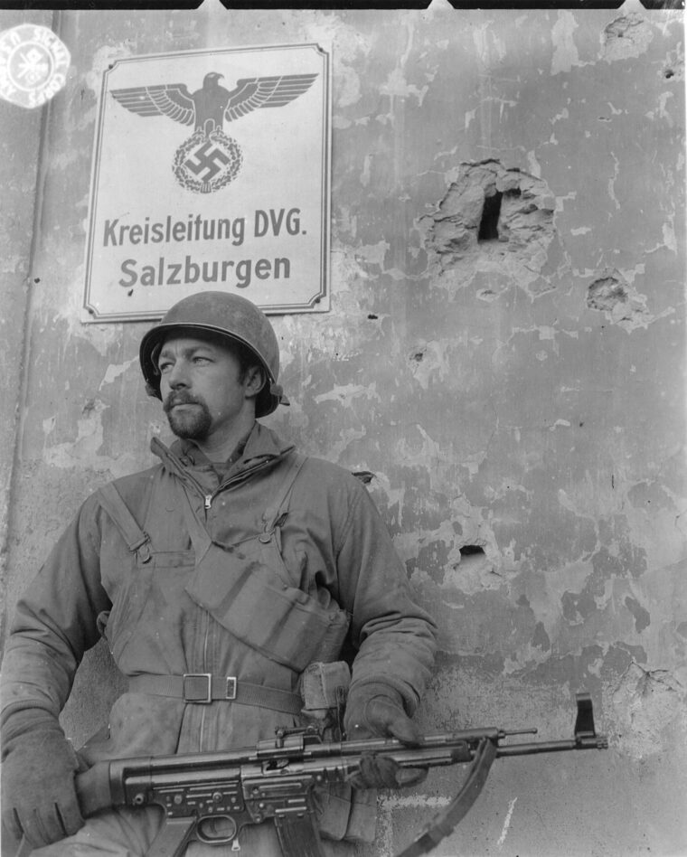 Sergeant Oakly M. Rath holds a captured German Sturmgewehr 44 in front of a chateau in Salins, France.