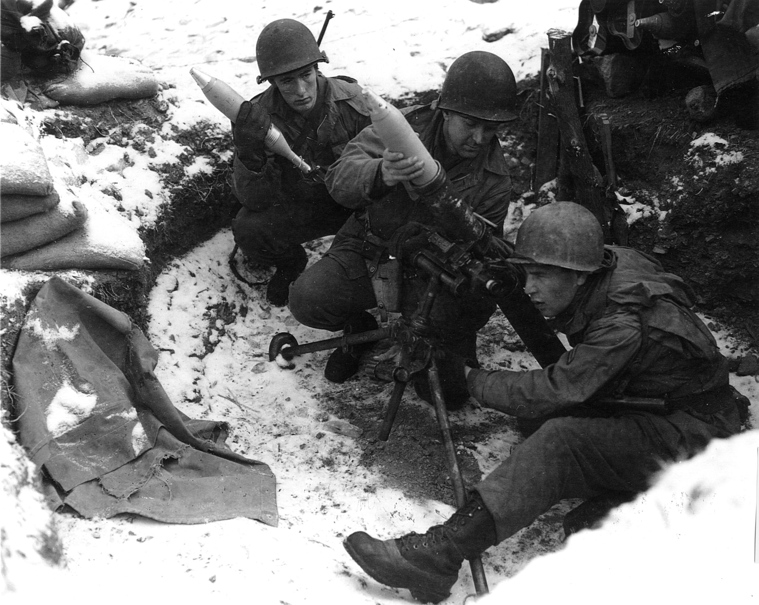 Americans fire a captured German mortar toward enemy positions.