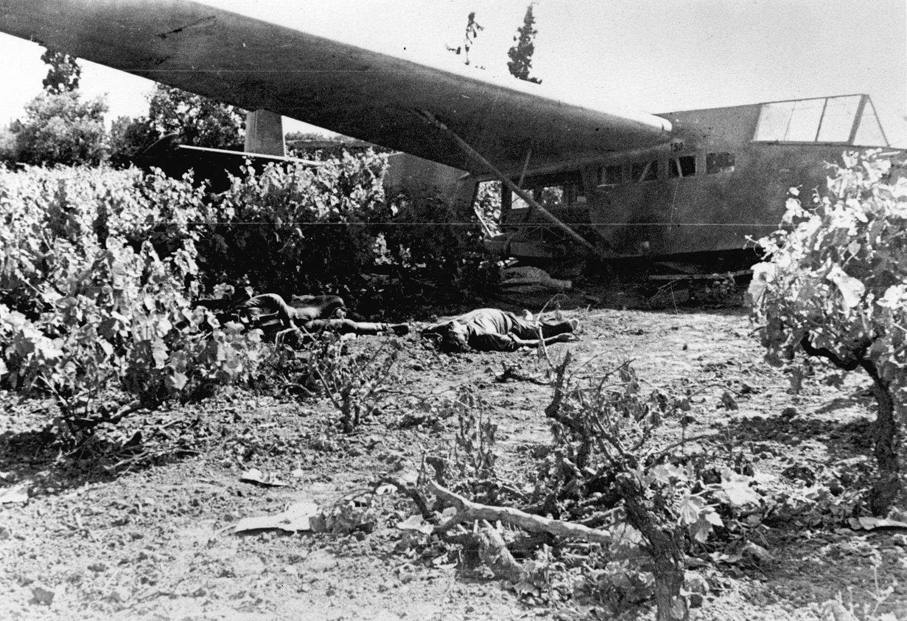 Dead German assault troops lie beside the wreckage of their glider. Many were killed before they could even exit the aircraft.