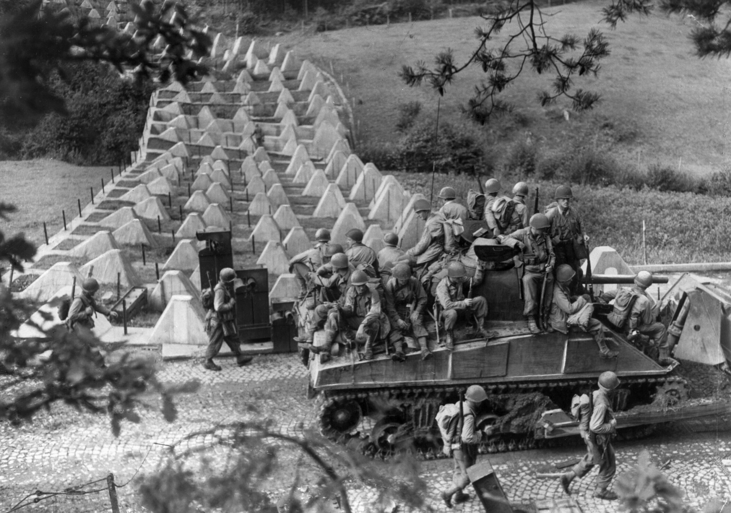 South of Aachen, American soldiers accompanied by an M-4 Sherman tank advance past “dragon’s teeth” tank obstacles on the Siegfried Line. Once inside the city, tanks lost much of the advantage of maneuver and firepower which they utilized in open country. (National Archives)