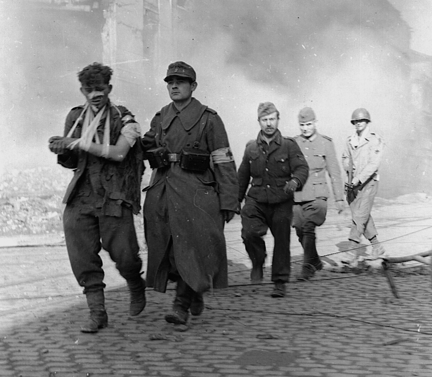 On October 5, 1944, wounded German prisoners are marched westward through the now quiet streets of Aachen. The U.S. 1st and 30th Divisions lost approximately 4,400 killed and wounded during the fight for the city. (National Archives)