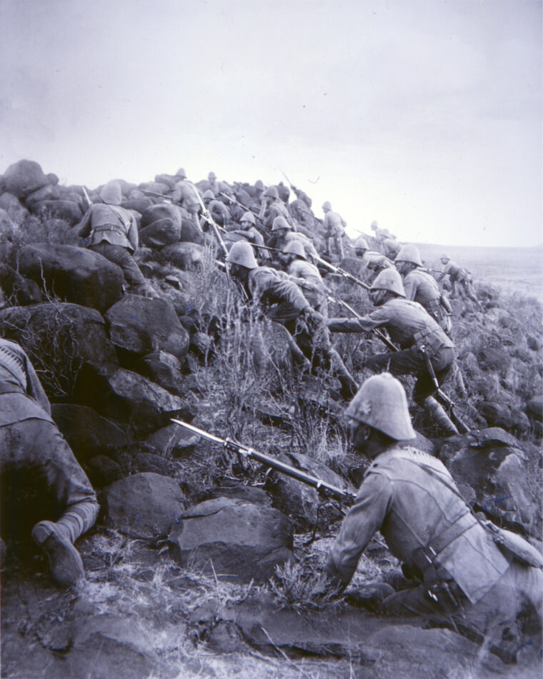 Carefully keeping their heads down, Canadian soldiers storm an outlying kopje, or small hill, in front of the main Boer trench line at Paardeberg Drift.