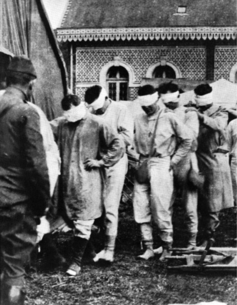 American victims of poison gas shuffle blindly through a French hospital courtyard during World War I.