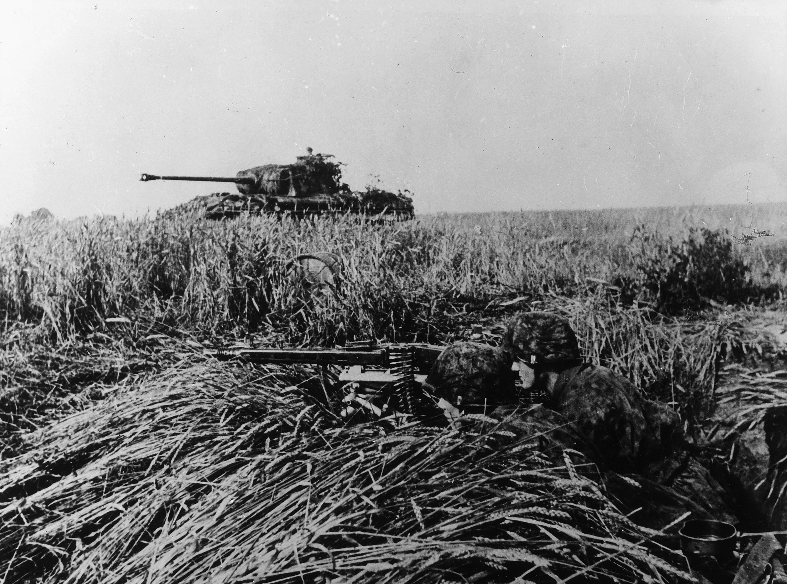Supported by a Panther medium tank, a pair of SS panzergrenadiers man a well-camouflaged machine-gun position and await an Allied attack. This photo was taken in July 1944. 
