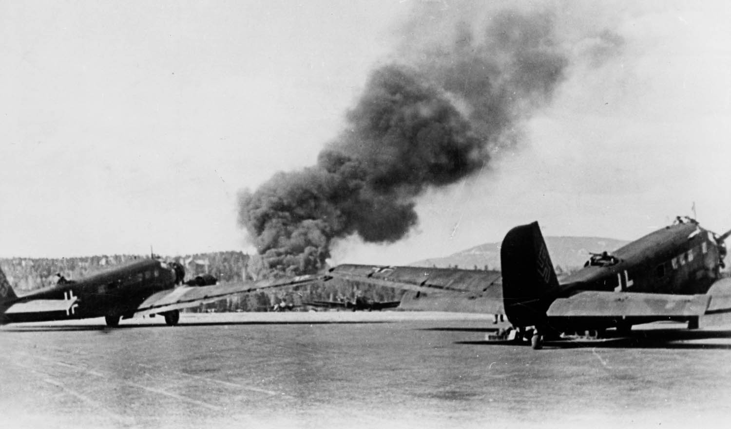 German planes sit on the airfield at Fornebu, near the Norwegian capital of Oslo, in April 1940, as smoke from a British air raid rises in the background.