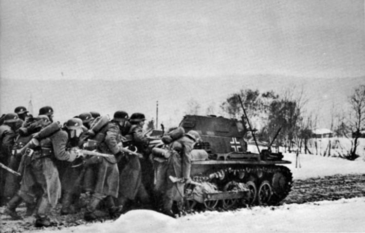 Crouching behind the cover of a Panzer I tank mounting twin machine guns, German infantrymen advance cautiously along a muddy road in central Norway. Still blanketed by spring snow, the countryside posed a challenge to logistics and rapid operations.