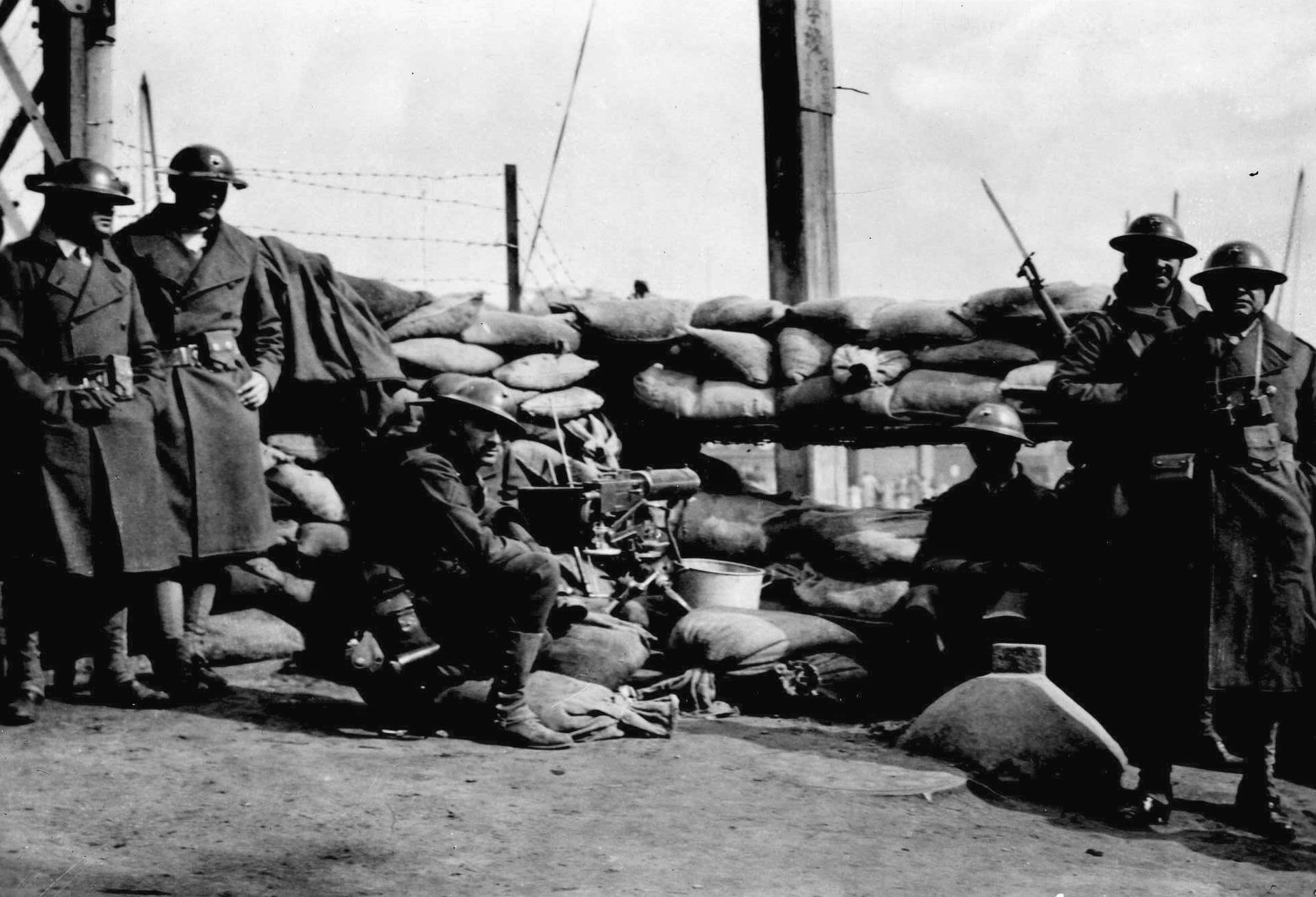 During a pause in the frenzied flight of Chinese refugees from fighting between the Japanese and Allied forces, U.S. Marines take cover behind a barricade of sandbags and man a machine gun near a bridge across Soochow Creek. (National Archives)