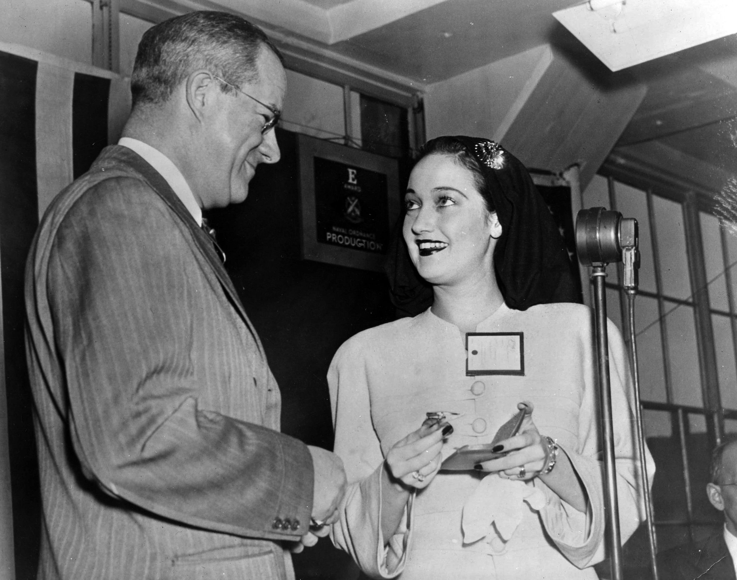 At the Bausch & Lomb plant in Rochester, New York, actress Dorothy Lamour makes an appearance to kick off a week-long campaign to sell war bonds. Bausch & Lomb Vice President Carl S. Hallauer presents the actress with a memento of her visit.