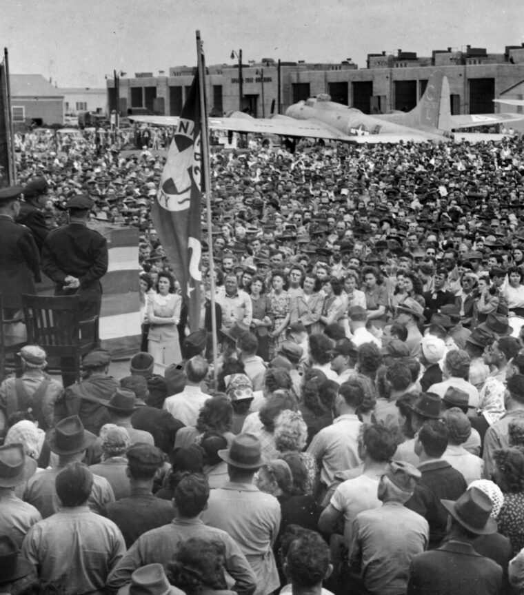 Colonel Leslie G. Mulzer, commander of the Oklahoma City Air Technical Service Command, accepts a Minute Man Pennant in recognition of record participation during the Sixth War Loan. Civilian and military personnel watch the ceremony, which, in itself, generated additional war bond sales.