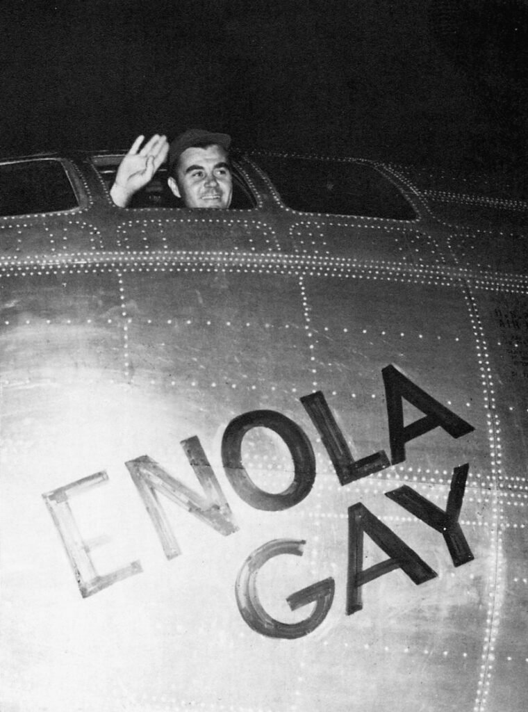 Colonel Paul W. Tibbets, pilot of the B-29 Superfortress Enola Gay, waves from the cockpit of the plane that dropped the Hiroshima bomb.