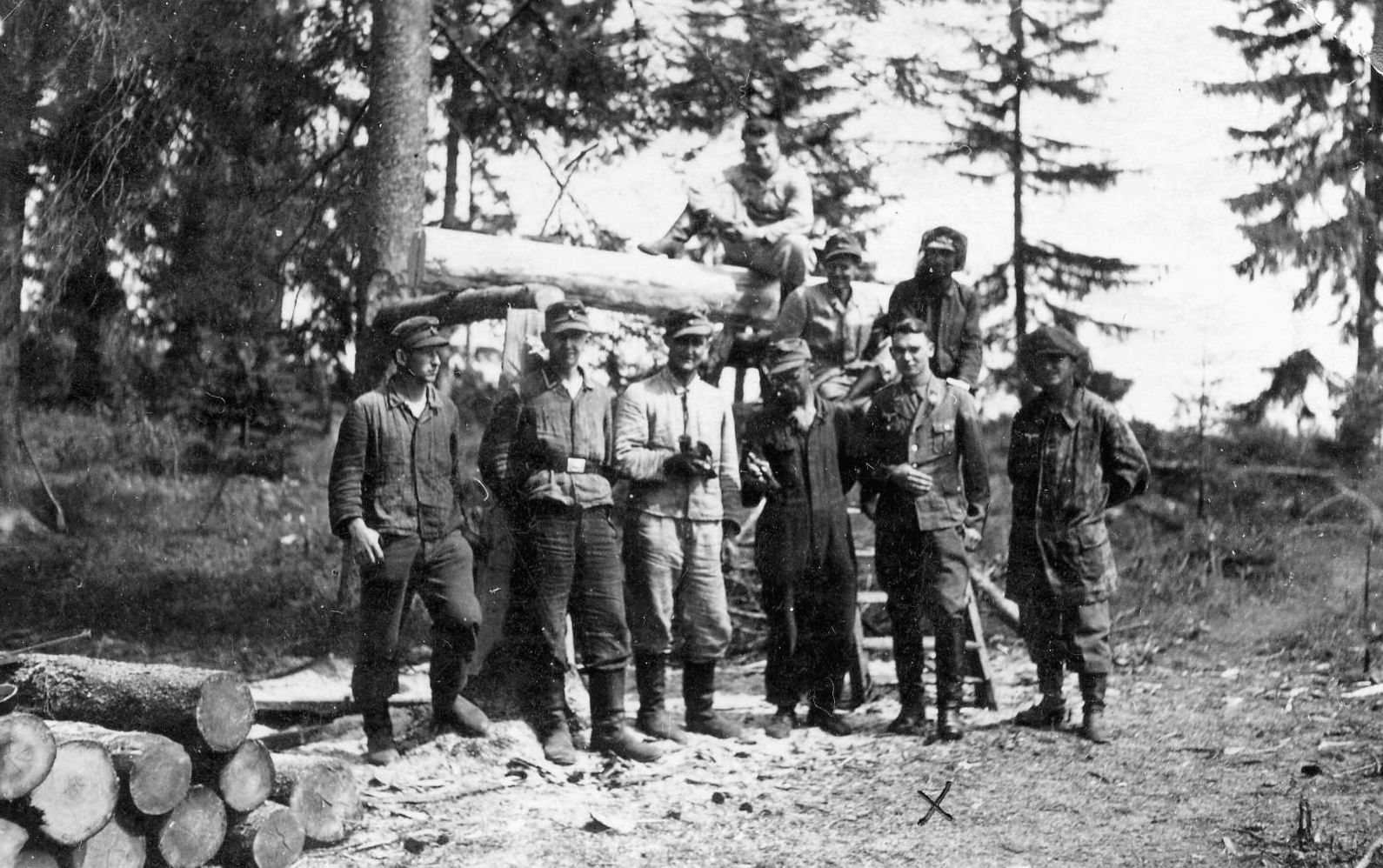 Benz says, “The 5th Battery Calculation Section, located in the woods, with our CO 1st Lieutenant Sauer standing second from the right. I am sitting behind him and to the right. The man fourth from the left, wearing dark blue coveralls, is a truck driver. The NCO third from the left is holding a raven that he captured, tamed, and taught to speak.”