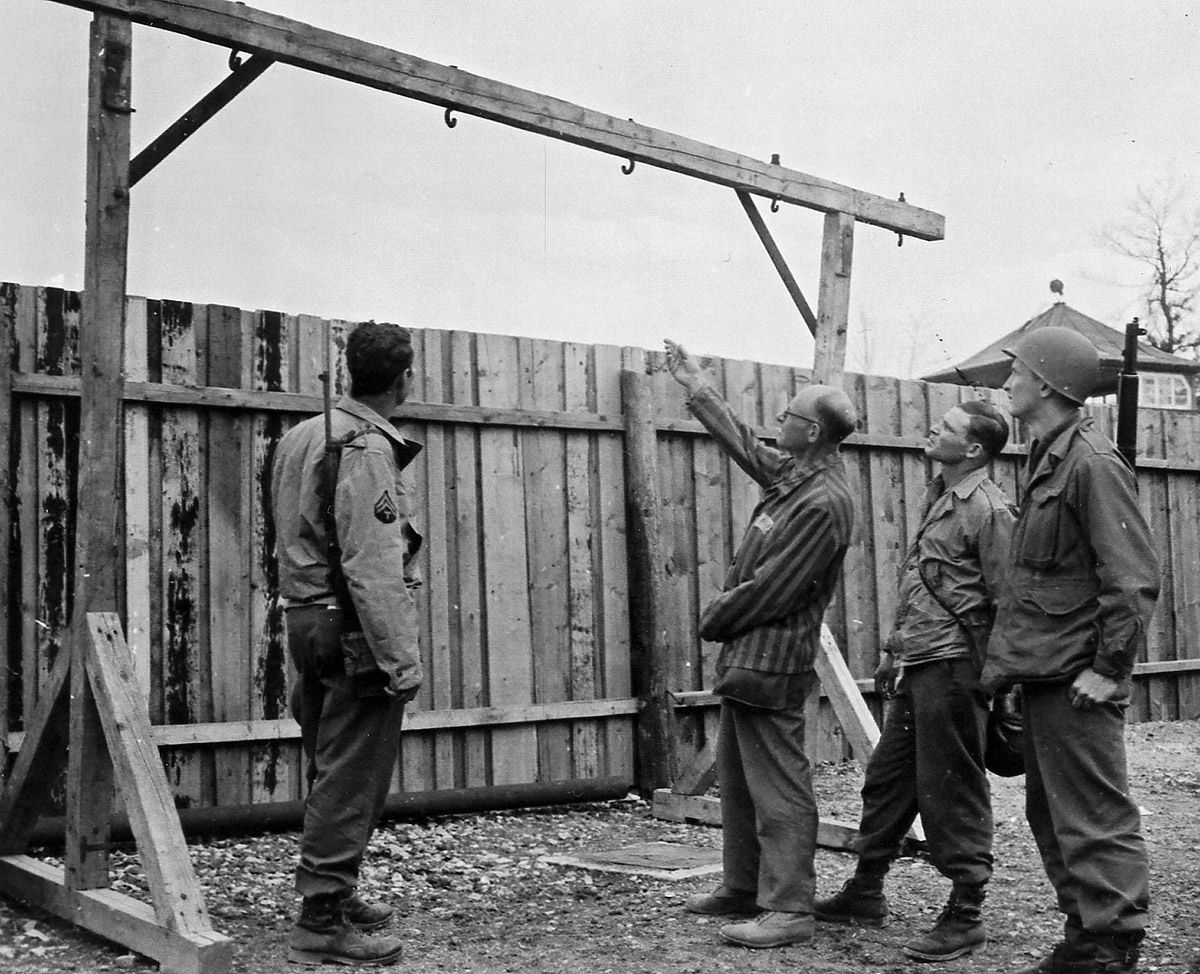 Following the liberation of Buchenwald, an inmate shows two American soldiers the prison gallows. A number of inmates were executed using this instrument of death. (National Archives)