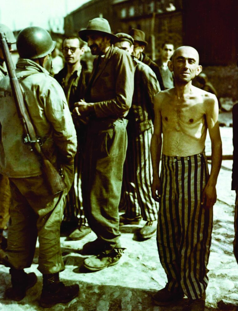 In this well-known photograph, American soldiers talk to newly liberated prisoners of the concentration camp at Buchenwald. Some are still wearing their striped prison uniforms, which were supplied to them by the Germans. 